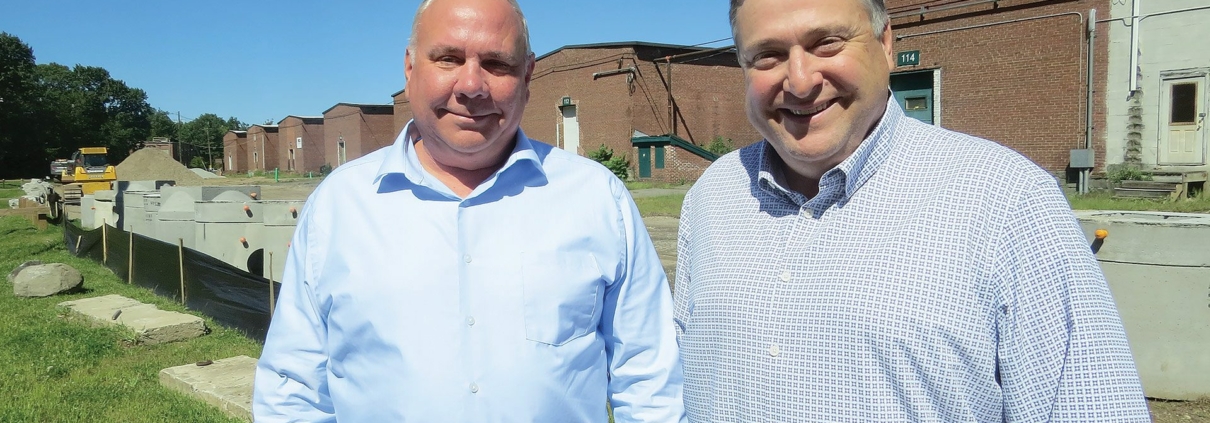 Jeff LeSiege, left, and Jeff Daley stop by one of two large parking lots being created at Ludlow Mills.